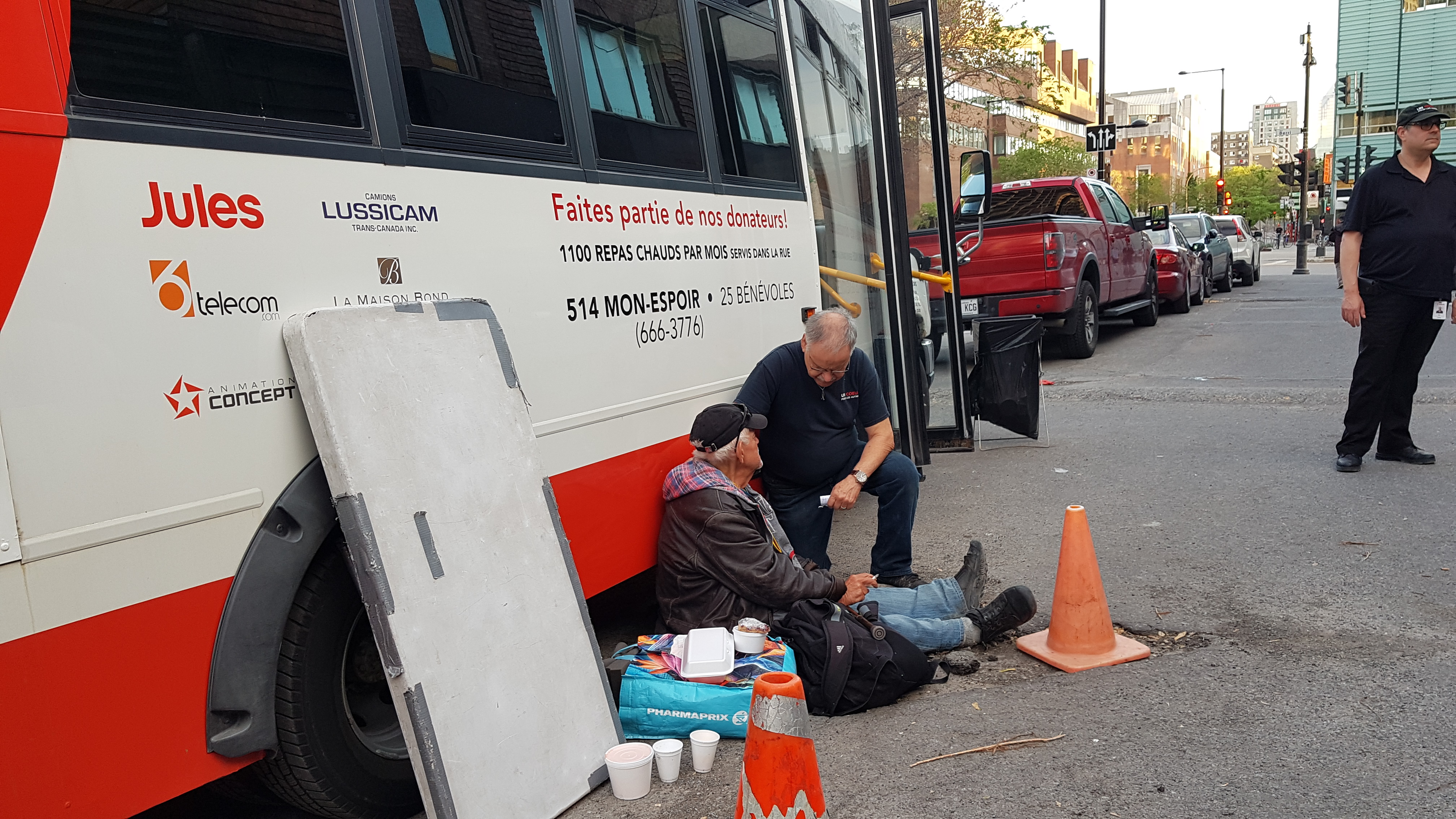 Homme assis sur le trottoir interagissant avec un intervenant près d'un camion