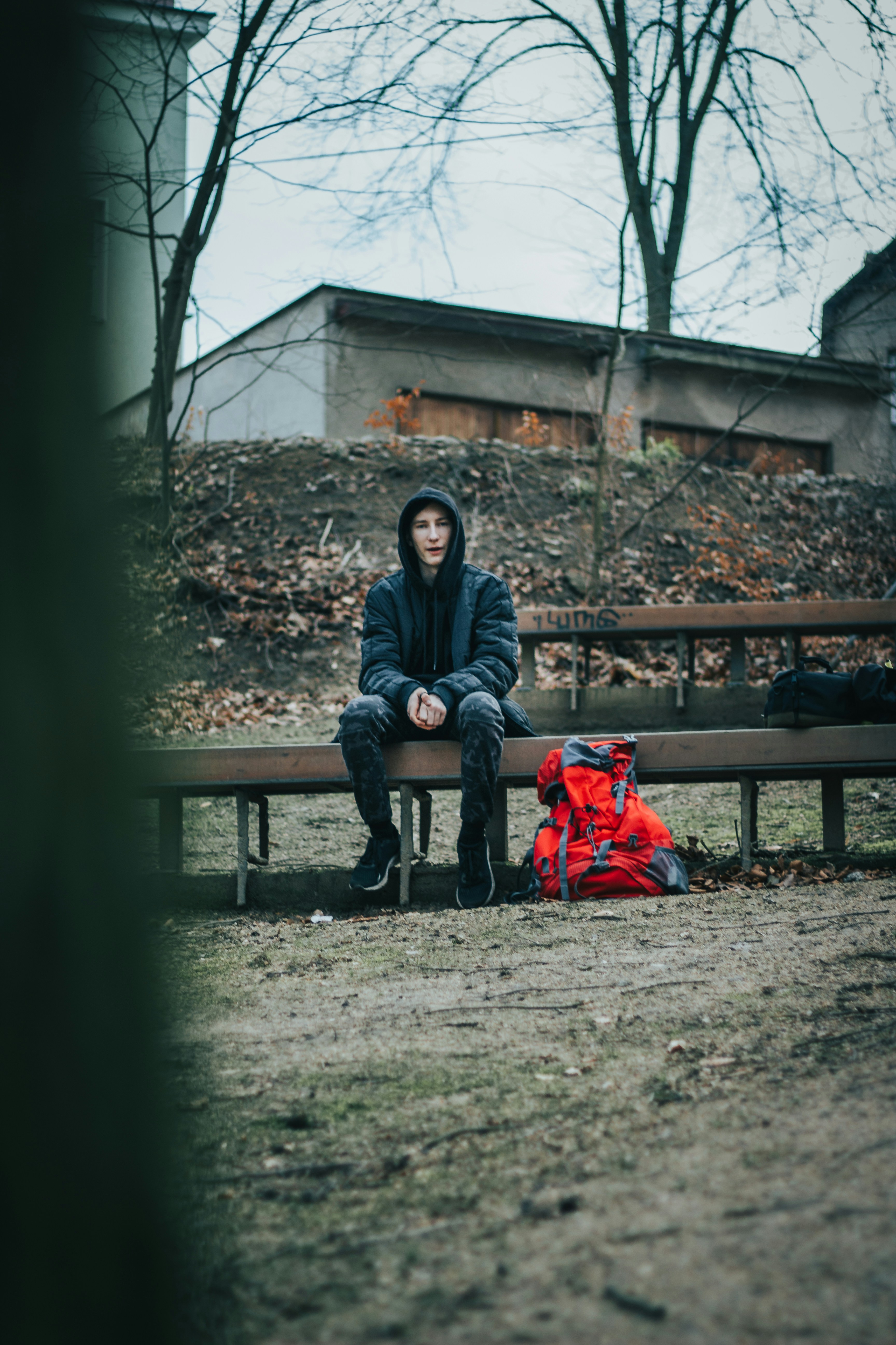 Jeune personne assise seule sur un banc public avec un sac à dos